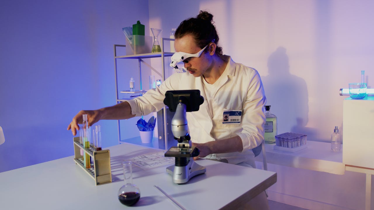 A researcher in a lab coat uses a microscope at a modern laboratory setup.